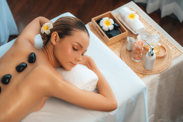 Hot stone massage at spa salon in luxury resort with day light serenity ambient, blissful woman...