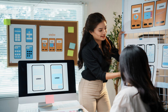 Two female web designers are having a discussion about user interface design while looking at a digital tablet in their office