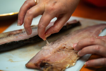 women's hands delicately extracting a fish bone, symbolizing care, culinary skills, and connection to nature. The image captures the essence of tradition and mindfulness in cooking