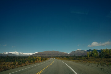 Scenic Route, Alaska Hwy, during a sunny and cloudy day. Mountains in Background.
