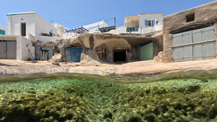 Underwater split photo of small cove and arch rock formations near  famous for colourful boat houses area of Karas, Kimolos island, Cyclades, Greece