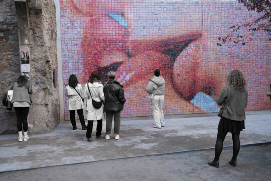 Barcelona, Espa&ntilde;a - 24 de enero de 2024: Varias mujeres est&aacute;n mirando el Mural del Beso del artista Joan Fontcuberta realizado con fotos sobre mosaicos. 
