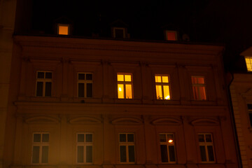 The windows of a large and impressive building are beautifully lit up at night, creating a striking...