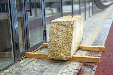 large concrete block rests on planks by a door, symbolizing obstruction and security. It evokes...
