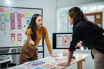 Two female uiux designers discussing over new mobile application design project in modern office