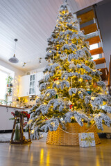 Festive Christmas decor in white kitchen, modern village interior with a snowy Christmas tree and fairy lights. New Year, Christmas mood, cozy home, Metal modular staircase. The general plan