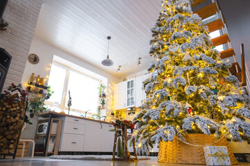 Festive Christmas decor in white kitchen, modern village interior with a snowy Christmas tree and fairy lights. New Year, Christmas mood, cozy home, Metal modular staircase. The general plan