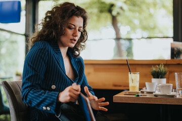 Businesswoman in a blue suit working at a cafe, focusing on her task with determination and...
