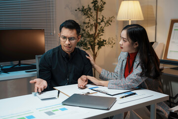Businesswoman is comforting her stressed male colleague while working late in the office