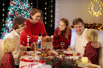 Family with kids having Christmas dinner at tree