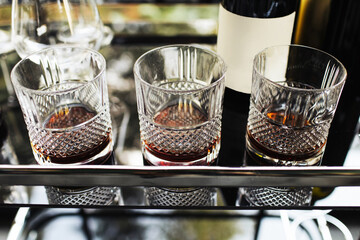 Three crystal glasses of whisky on a home bar with warm, atmospheric lighting creating a cozy and inviting ambiance. Intimate evening or casual gathering. Alcohol drinking background.