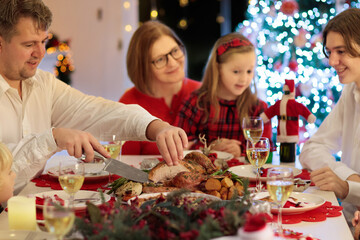 Family with kids having Christmas dinner at tree