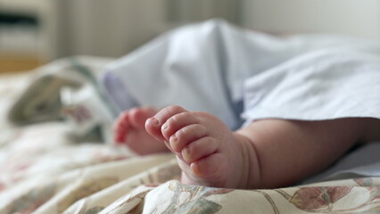 Fototapeta premium Close-up of a baby’s tiny foot resting on a patterned bedspread. the delicate details of babyhood in a cozy, indoor environment