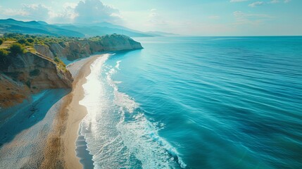Aerial view of a stunning Mediterranean beach. The blue sea glistens under the sun, waves gently breaking on the shore. A serene and beautiful scene