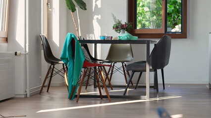 Dining room with multiple chairs arranged around a table, featuring a teal jacket draped over one...