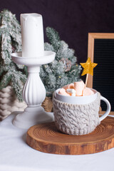 A New Year's festive hot drink with marshmallows next to the Christmas tree on the table. the concept of the New Year