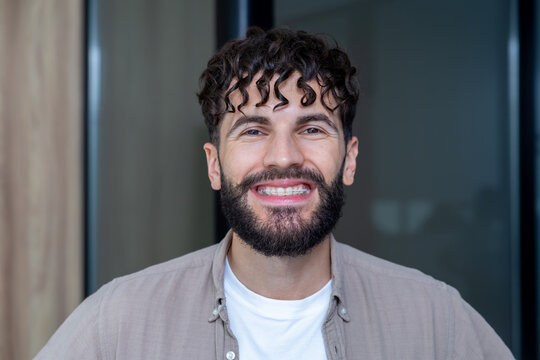 Man with cheerful smile showing clear ceramic braces on his teeth after dentist visit