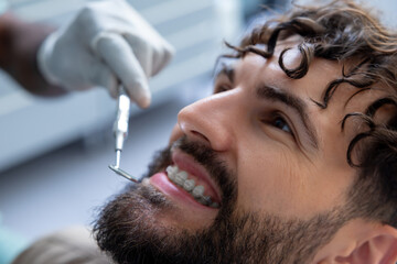 Unrecognizable dentist examining patient’s teeth using specialized dental tools