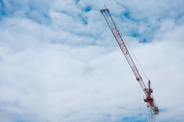 The crane works against the blue sky. Construction, investment, real estate sales. Space for text.