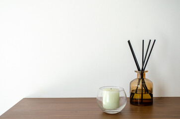 Air freshener and candle on wooden table, daylight, environmental comfort.