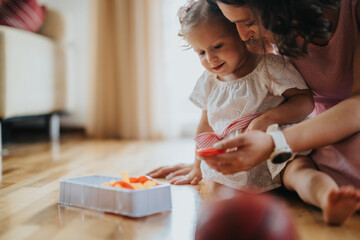 A mother and her young daughter playing together at home, fostering a warm and loving family environment.