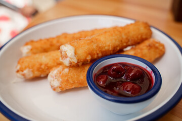 Deep-fried cheese sticks with cherry sauce.