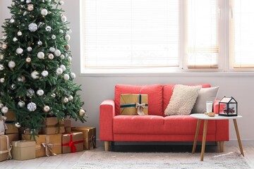 Interior of light living room with pink sofa and gifts under Christmas tree