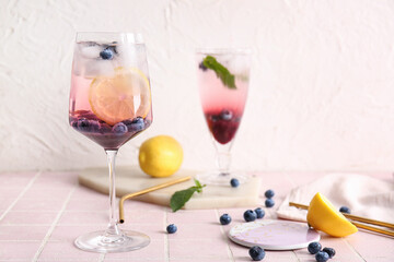 Glasses of fresh blueberry lemonade with mint on pink tile table