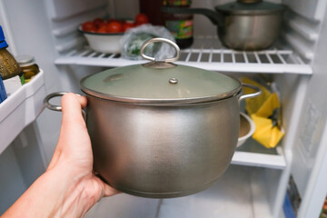 A hand taking a pot from a frige, refrigerator. Home cooking and healthy food concept