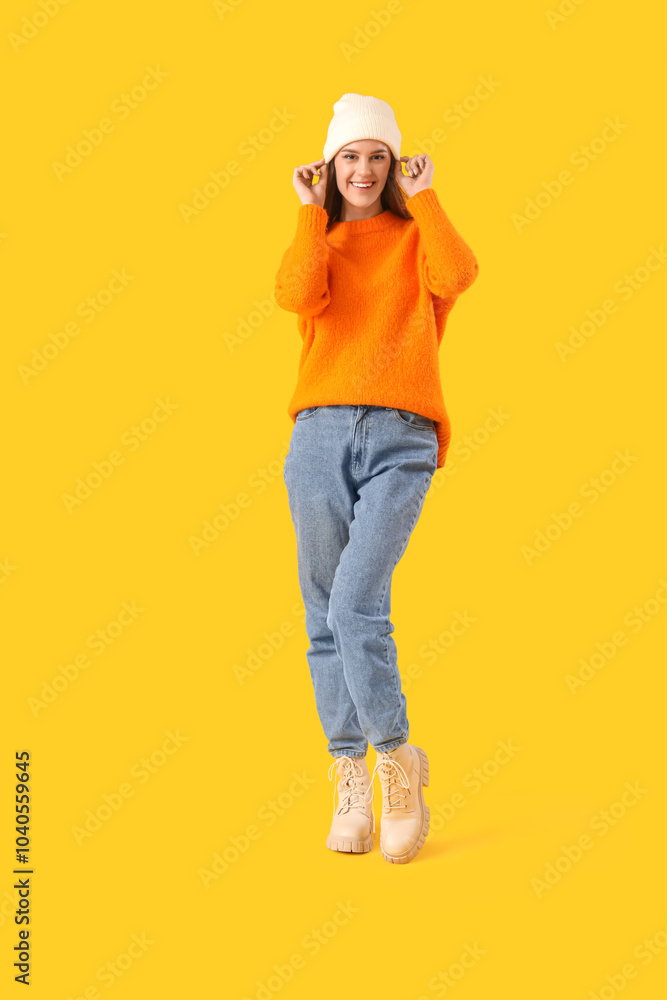 Canvas Prints Young woman in winter clothes on yellow background