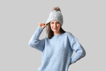 Young woman in winter clothes on light background