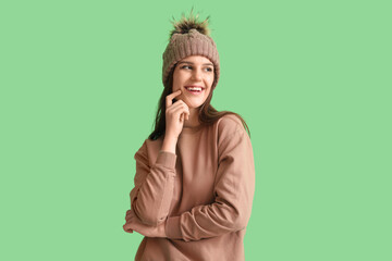 Young woman in winter clothes on green background