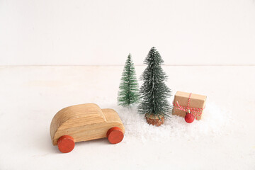 Wooden toy car with Christmas trees and gift box on white background