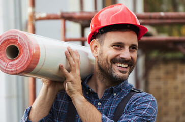 Construction worker carrying roll on shoulder on building site