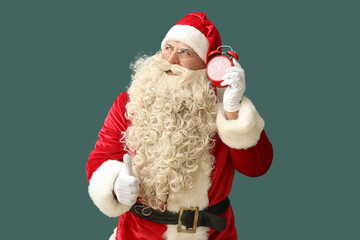 Santa Claus with alarm clock showing thumb-up on green background