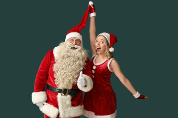 Happy Santa Claus with beautiful woman showing thumb-up on green background