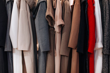 Brown beige grey autumnal coats hanging in a row on hangers in a winter clothing boutique for women