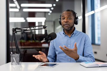 Professional african american businessman podcasts with microphone, headphones. Engaged in voice...