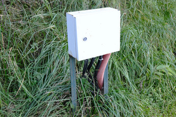 Outdoor electrical distribution box for landscape lighting, close-up on green lawn background