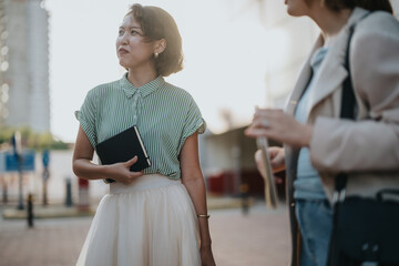 A diverse group of business people engaged in a meeting outdoors, focusing on collaboration and teamwork in a sunny urban environment.