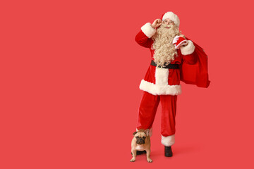 Santa Claus with bag and French bulldog on red background