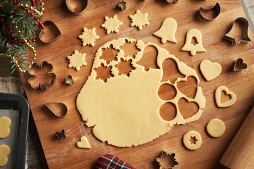 Cutting out various shapes from rolled out pastry dough to prepare homemade Linzer Christmas cookies