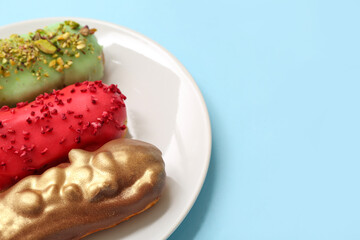 Plate with tasty glazed eclairs on color background