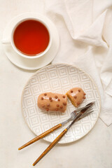 Plate with sweet eclair and tea on light  background