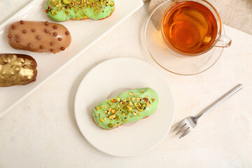 Sweet eclairs and tea on light  background