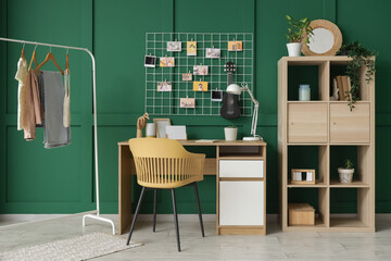 Interior of office with workplace, mood board and clothes rack