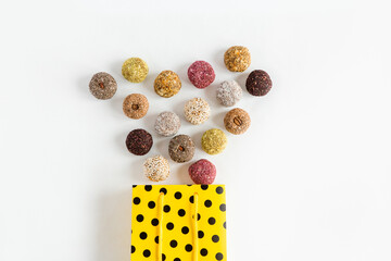 Healthy sweets, candies made from natural ingredients., crumble out of the yellow festive bag. Vegetarian organic food. White background, birthday and party concept.