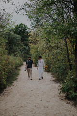 Obraz premium Two friends stroll down a scenic forest path, engaged in a relaxed conversation. The lush greenery adds a sense of tranquility and connection with nature.