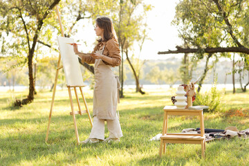 Female artist painting on canvas in park