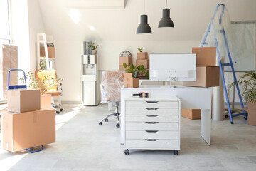 Workplace with cooler and cardboard boxes in office on moving day